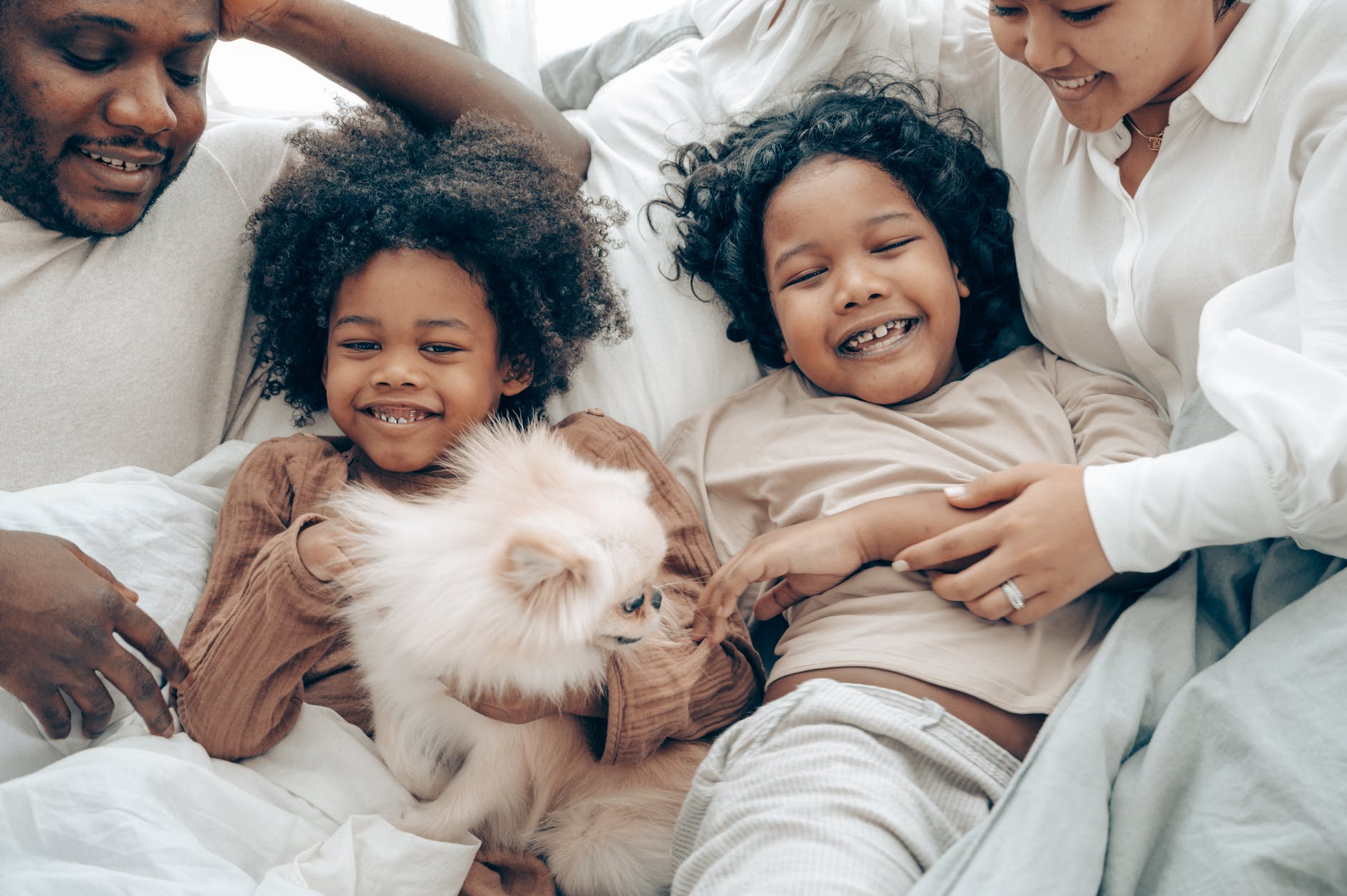 cheerful multiracial family having fun in bed during weekend
